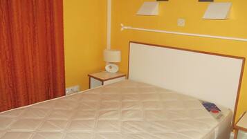 2 dormitorios y tabla de planchar con plancha