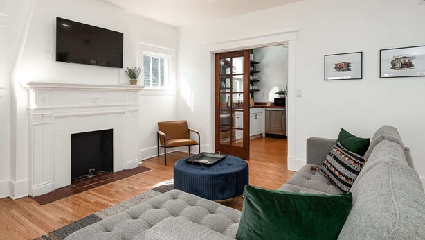Ein Wohnzimmer mit Kamin, einer Couch, einem Fernseher und einer Küche im Hintergrund.
