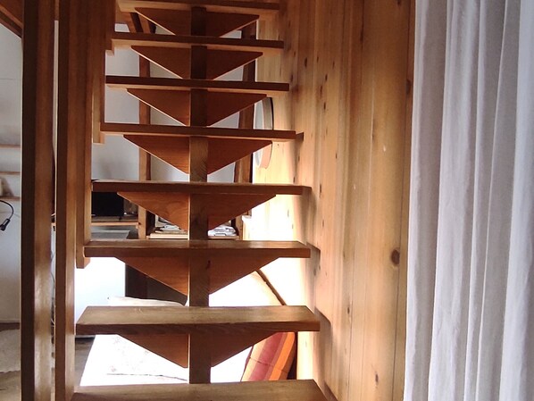 Un escalier en colimaçon en bois, composé de plusieurs paliers, menant à l’étage supérieur.