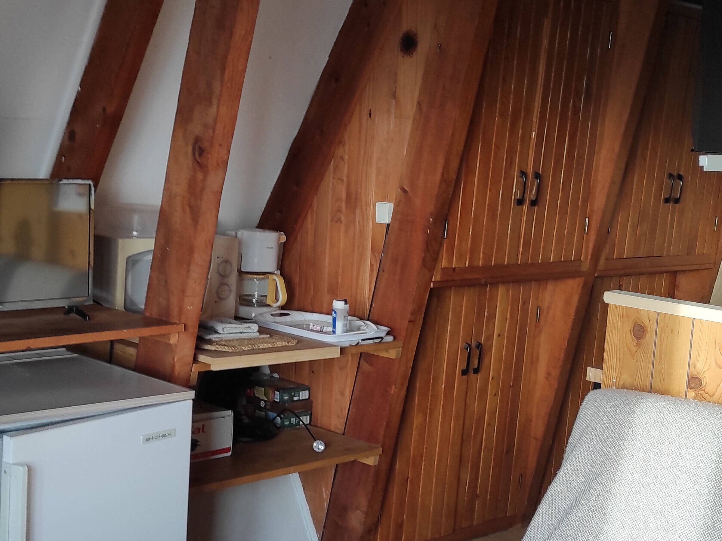 A compact kitchen with wooden cabinets, a small refrigerator, a coffee maker, and a microwave.