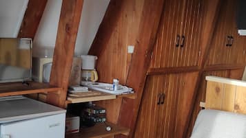 A compact kitchen with wooden cabinets, a small refrigerator, a coffee maker, and a microwave.