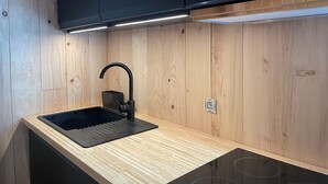 Una cocina moderna con un lavamanos negro, armarios de madera y una estufa integrada.