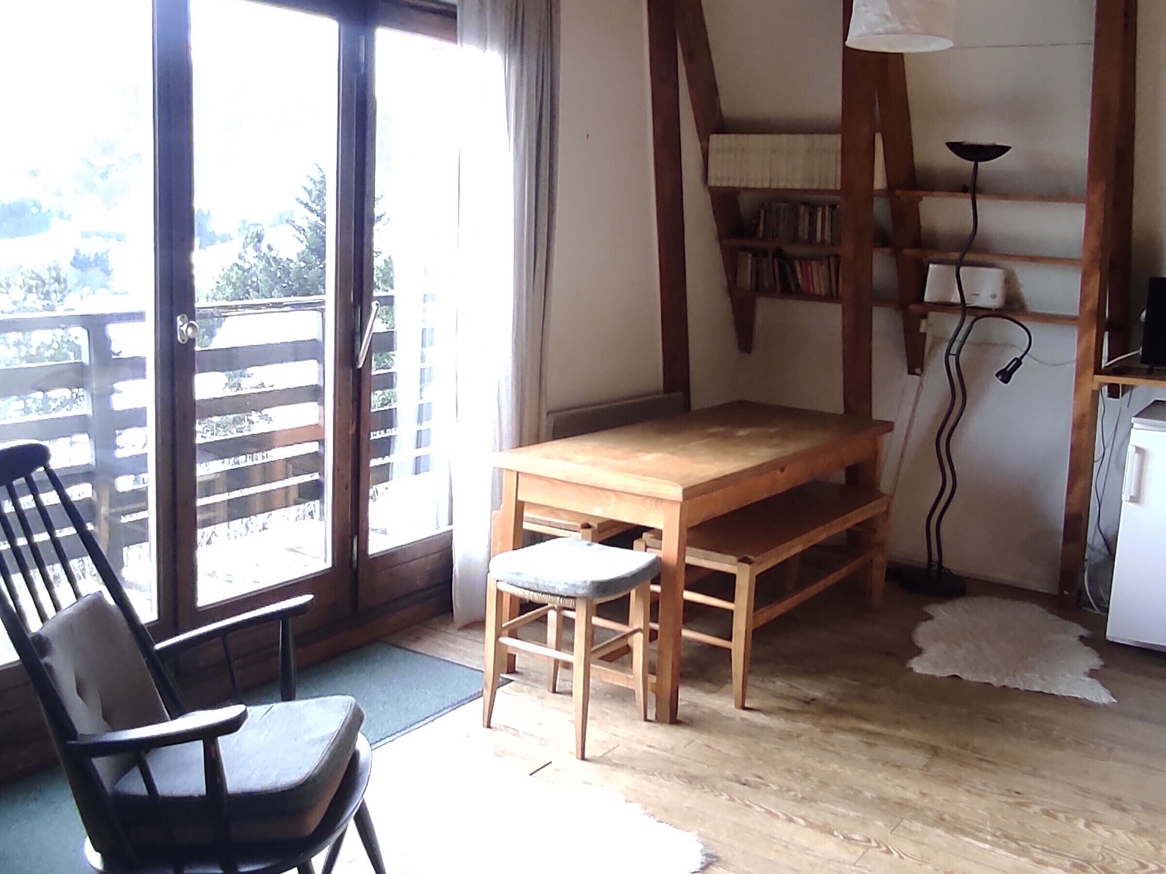 A room with a wooden table, a chair, a bookshelf, and a desk.