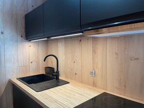Une cuisine moderne avec un évier noir, des armoires en bois et une cuisinière intégrée.