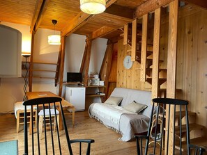 Ein gemütliches Blockhaushaus-Interieur mit einem Holzespeisesaal, Stühlen, einer Couch und einer Küchenzeile mit Mikrowelle und einer Uhr.
