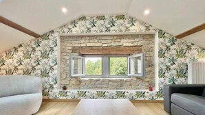 A room with a stone wall, a window, and a view of greenery. - Charming 4-Bedroom Cottage with Modern Comfort (Haroué)