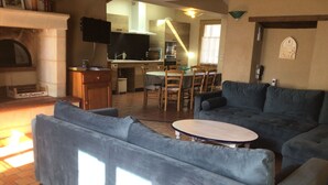 A living room with a fireplace, a dining area with a table and chairs, and a kitchen in the background.