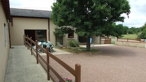 A building with a gravel driveway, a wooden fence, and a tree.