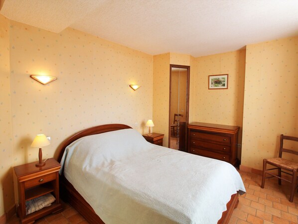 A bedroom with a bed, nightstands, a dresser, a chair, and a mirror.