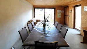A conference room with a long table, chairs, a potted plant, and a wooden ceiling.