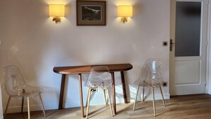 A room with a wooden table and two clear plastic chairs, a framed picture on the wall, and two wall-mounted lamps. - 2 rooms 4 pers 3* in Valloire, south, WiFi, parking, balcony (Valloire)