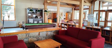 A cozy room with a pool table, red sofas, and a wooden coffee table.