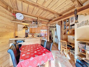 A wooden interior with a dining table, chairs, a kitchen area, and a bookshelf. - Charming apartment for 6, La Clusaz, with Wifi (La Clusaz)
