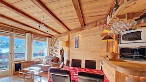 Un interior acogedor de madera con comedor, chimenea y vistas al exterior.