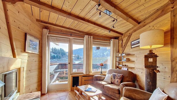 Interior acogedor de una cabaña de madera con sofá, mesa de centro y chimenea.