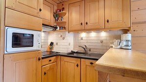 Una cocina compacta con armarios de madera, horno empotrado, pileta y cafetera.