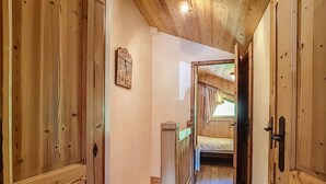 Un interior de madera con un estrecho pasillo que lleva a un dormitorio con literas.