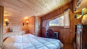 Un dormitorio de cabaña acogedor, con cama, escritorio y ventana con cortinas.