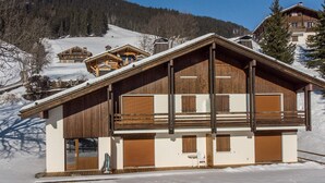 A two-story wooden chalet with a sloped roof, large windows, and a balcony. - Cozy apartment in La Clusaz, perfect for 6 guests, with 3 bedrooms (La Clusaz)