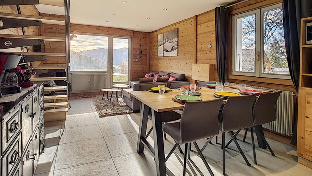 A cozy cabin interior with a dining area, wooden walls, and a view of mountains. - Cozy apartment in La Clusaz, perfect for 6 guests, with 3 bedrooms (La Clusaz)