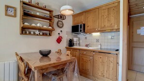 Eine Küche mit Holzausstattung, einer Mikrowelle, einem Spülbecken und einem Holztisch mit Stühlen.