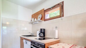 Una cocina compacta equipada con lavavajillas, horno, cafetera y un refrigerador pequeño.