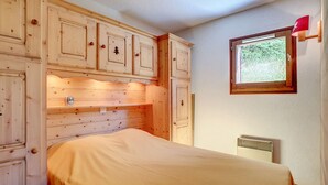 Un dormitorio con paneles de madera, una cama, un ventanal con vistas y un radiador.