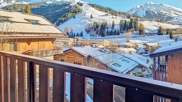 Un paisaje montañoso con edificios nevados y una terraza de madera.