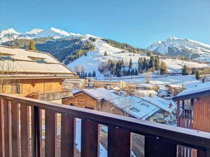 Un paisaje montañoso con edificios nevados y una terraza de madera.
