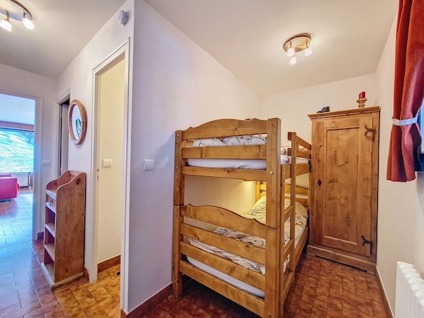A room with a bunk bed, wooden wardrobe, and a radiator.