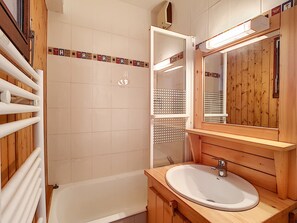 A bathroom with a wooden vanity, a white sink, and a bathtub. - Cozy studio for 4 in La Clusaz with balcony and garage (La Clusaz)