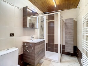Een moderne badkamer met douchecabine, wastafel met spiegel en handdoekrek.