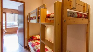 Ein Schlafsaalzimmer mit Etagenbetten, einer Holztür und einem Fenster.
