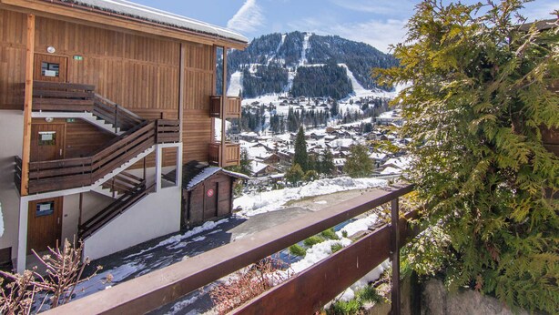 Ein Holzgebäude mit Treppe und Blick auf eine verschneite Berglandschaft.