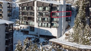 Un hotel de varios pisos con balcones, rodeado de árboles nevados y un paisaje montañoso.
