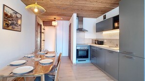 Una cocina moderna con armarios grises, horno empotrado y una mesa de comedor de madera para cuatro comensales.