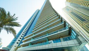Un immeuble moderne de grande hauteur, doté de nombreux balcons et d’une façade incurvée.