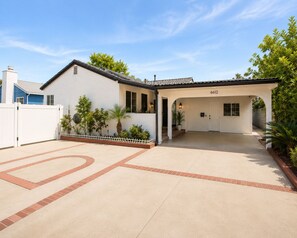 Een gelijkvloers huis met een witte gevel, een overdekte oprit en het nummer '6612' op de voordeur.