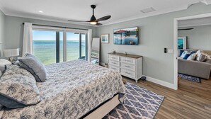 Ein Schlafzimmer mit Bett, Kommode, Fernseher und Meerblick.