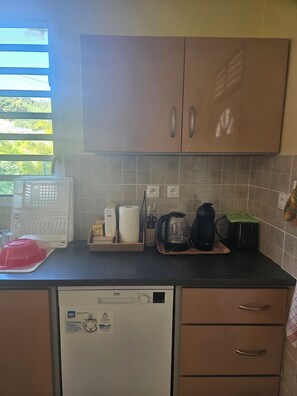 Kitchen area with a dishwasher, coffee maker, kettle, and ample counter space.