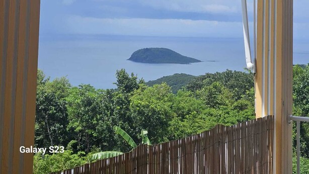 A balcony with a view of the sea and a distant island. - House between mountains and sea. (Deshaies)