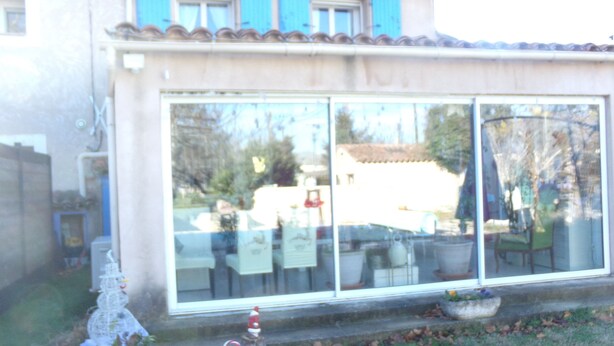 Ein Gebäude mit großen Glasfenstern, einem Ziegeldach und blauen Fensterläden.
