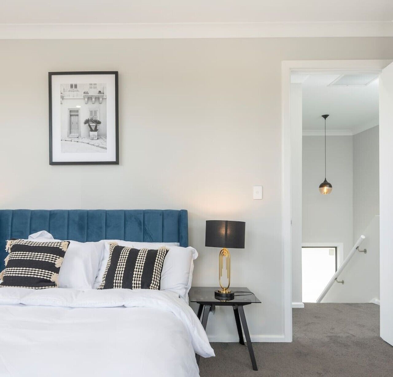 A bedroom with a bed, a nightstand, a lamp, and a framed picture on the wall.