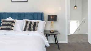 Ein Schlafzimmer mit einem Bett, einem Nachttisch, einer Lampe und einem gerahmten Bild an der Wand.