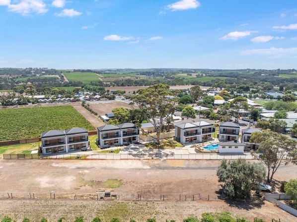 Zona residencial con casas modernas, una piscina y un viñedo al fondo.