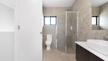 Une salle de bain moderne avec une douche à parois de verre, des toilettes blanches et un grand lavabo blanc.