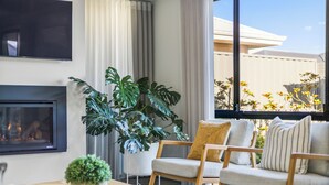 A modern living room with a fireplace, comfortable seating, and large windows offering a view of the outdoors.