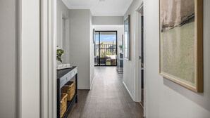 A hallway with a view to a balcony, a framed artwork on the wall, and a wicker basket on the floor.