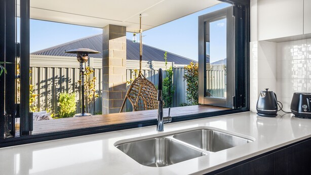 A kitchen with a large window, a sink, and a kettle on the counter.