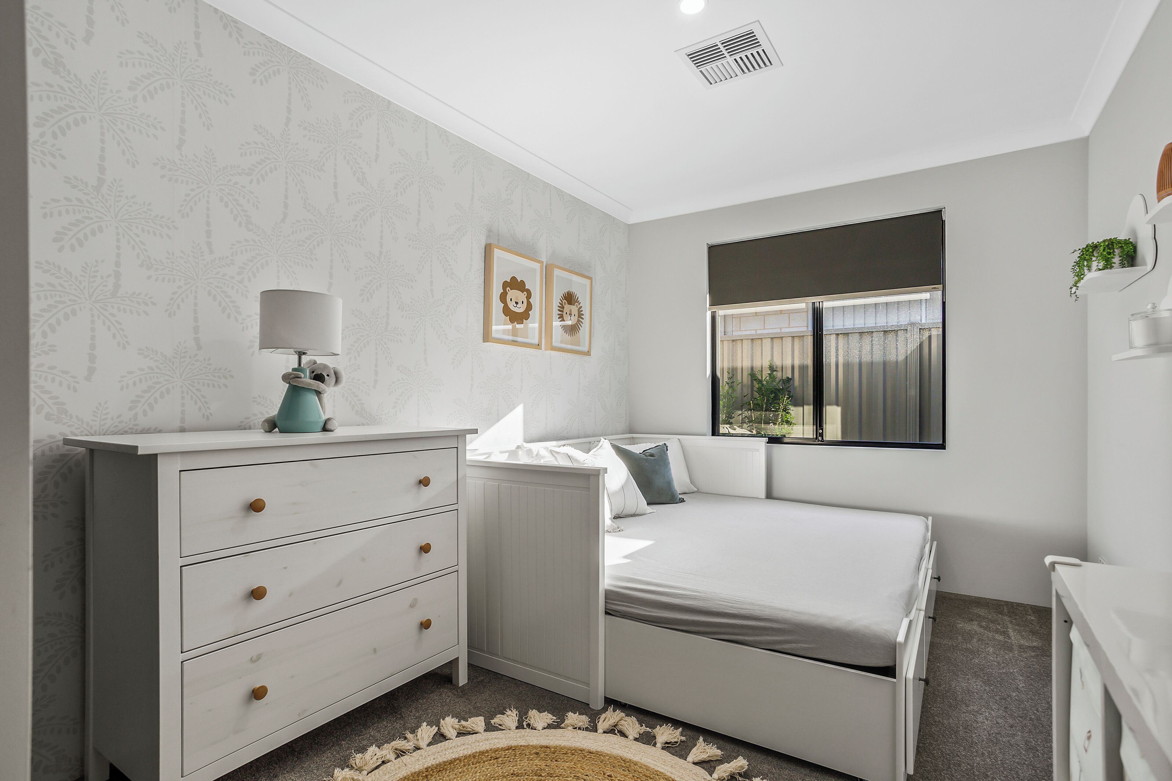 A bedroom with a bed, a dresser, a lamp, and two framed pictures on the wall.